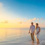 A couple enjoys a romantic walk on a sunny beach in the Maldives at sunrise.