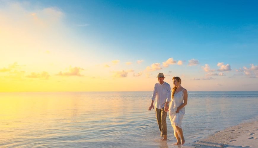A couple enjoys a romantic walk on a sunny beach in the Maldives at sunrise.