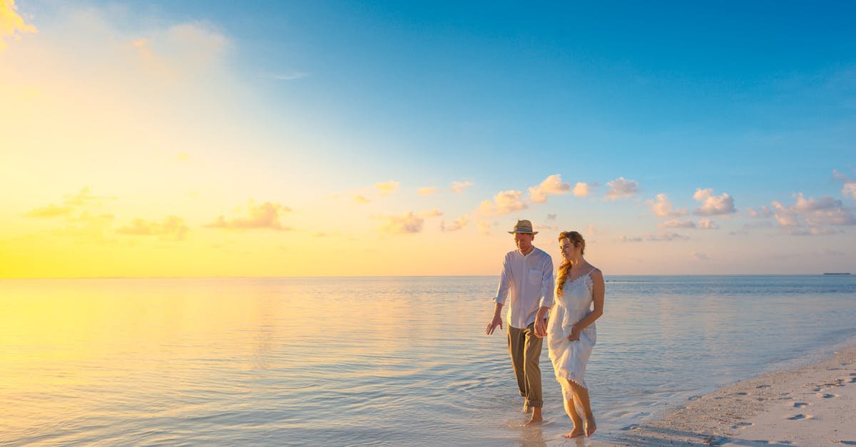 A couple enjoys a romantic walk on a sunny beach in the Maldives at sunrise.